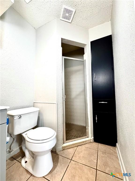 6430 Ridge Village Dr, San Antonio, TX 78233 - full bath featuring toilet, tile patterned flooring, a stall shower, a textured ceiling, and a textured wall