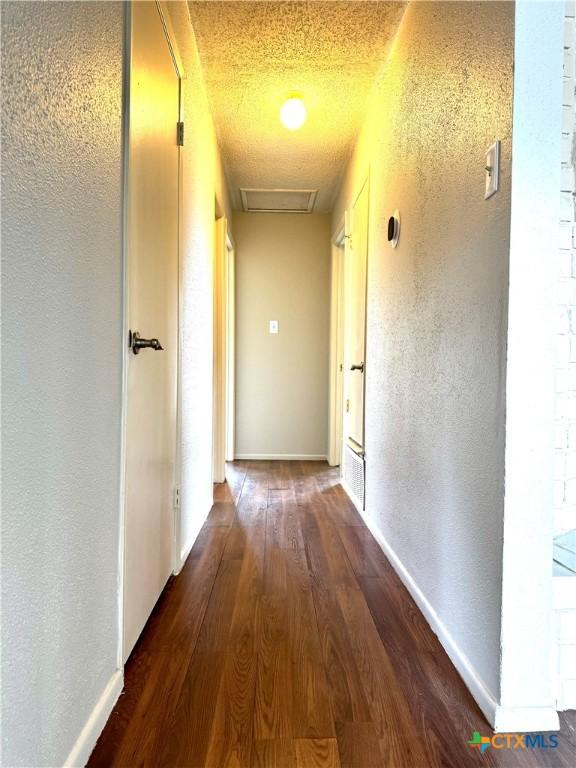 6430 Ridge Village Dr, San Antonio, TX 78233 - hallway featuring wood finished floors, baseboards, a textured wall, and attic access