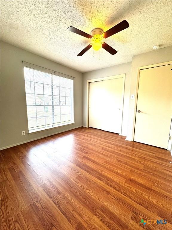6430 Ridge Village Dr, San Antonio, TX 78233 - unfurnished bedroom featuring wood finished floors, a textured ceiling, a closet, and ceiling fan