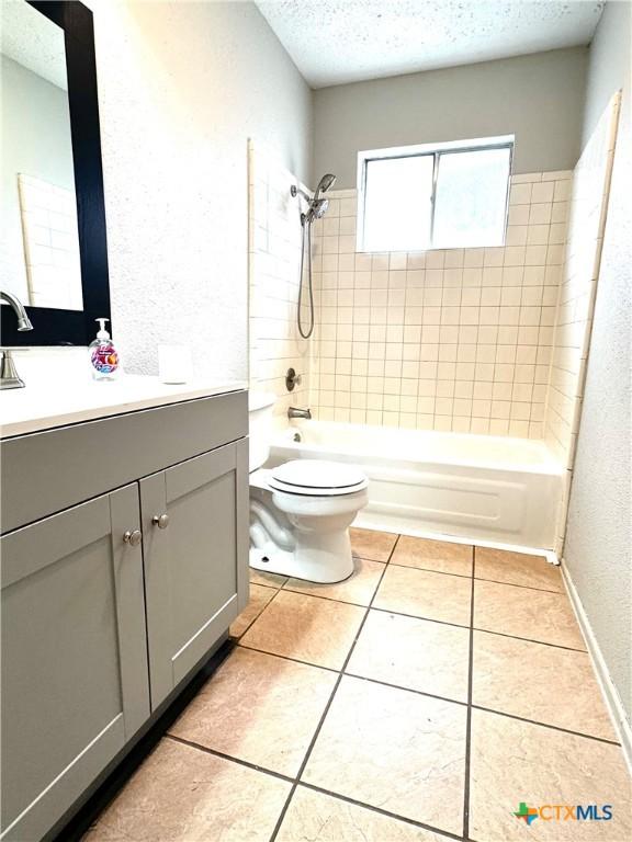 6430 Ridge Village Dr, San Antonio, TX 78233 - full bath with a textured ceiling, bathtub / shower combination, vanity, tile patterned flooring, and toilet