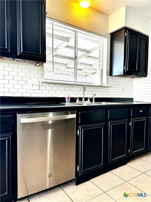 6430 Ridge Village Dr, San Antonio, TX 78233 - kitchen with stainless steel dishwasher, dark cabinetry, dark countertops, and backsplash