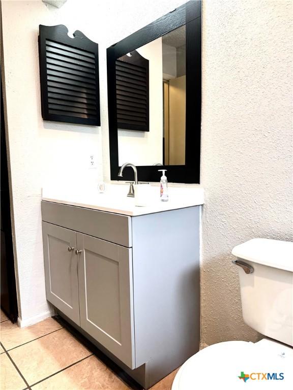 6430 Ridge Village Dr, San Antonio, TX 78233 - half bathroom with toilet, tile patterned floors, vanity, and a textured wall