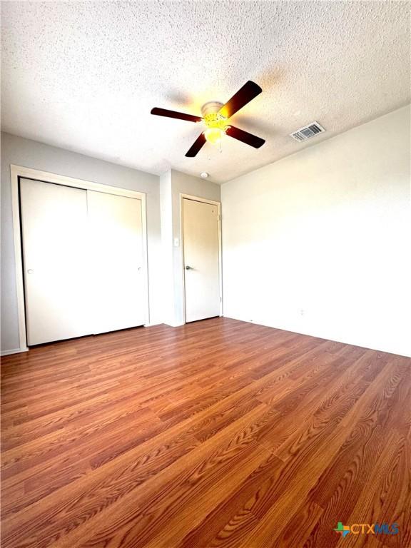 6430 Ridge Village Dr, San Antonio, TX 78233 - unfurnished bedroom featuring a textured ceiling, wood finished floors, a closet, and a ceiling fan