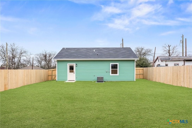 rear view of property featuring central AC and a lawn