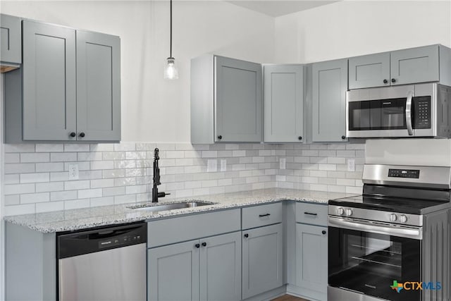 kitchen featuring decorative backsplash, stainless steel appliances, gray cabinets, and sink