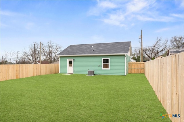 rear view of house featuring a lawn and central AC unit