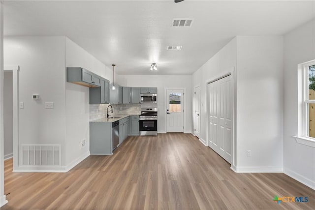 kitchen with gray cabinetry, a healthy amount of sunlight, sink, and stainless steel appliances