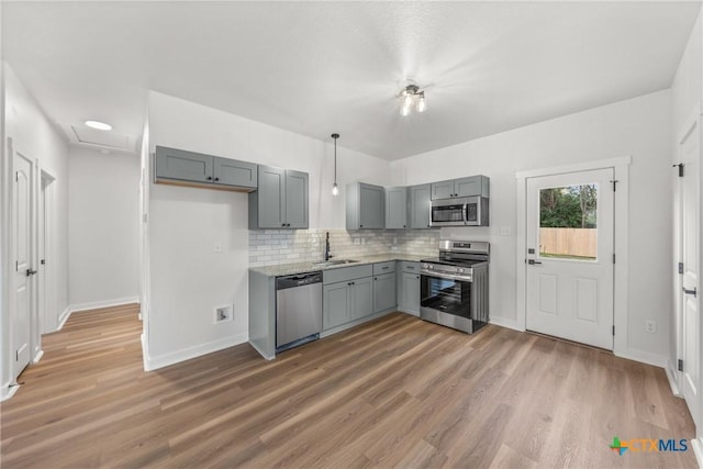 kitchen with gray cabinetry, sink, stainless steel appliances, dark hardwood / wood-style floors, and backsplash