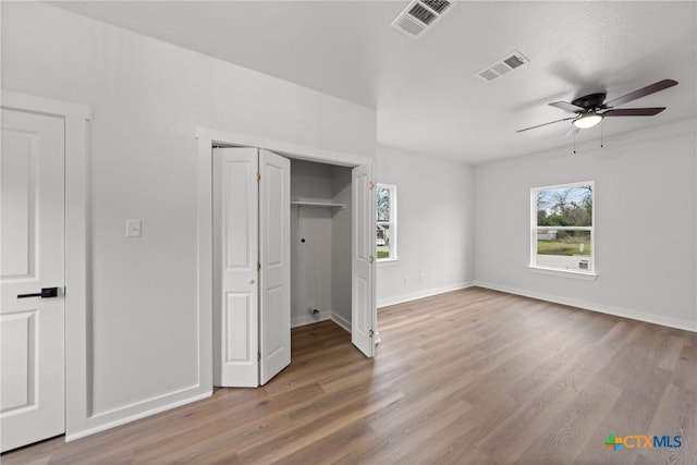 unfurnished bedroom with multiple windows, ceiling fan, and wood-type flooring