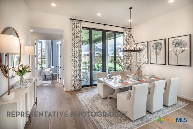 dining area featuring baseboards, wood finished floors, a notable chandelier, and french doors