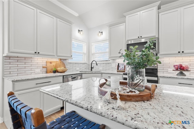 1827 Broken Shoe Trl, Temple, TX 76502 - kitchen featuring lofted ceiling, white cabinetry, appliances with stainless steel finishes, light stone countertops, and tasteful backsplash