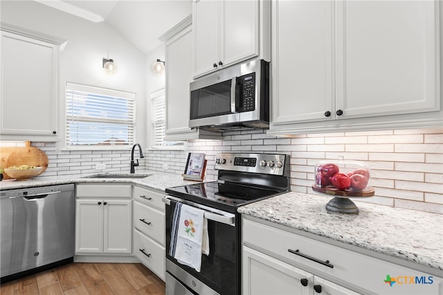1827 Broken Shoe Trl, Temple, TX 76502 - kitchen with appliances with stainless steel finishes, vaulted ceiling, white cabinets, tasteful backsplash, and light wood-style floors
