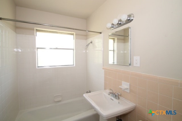 bathroom featuring tiled shower / bath combo, tile walls, and sink