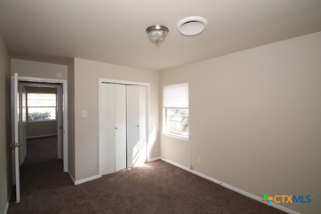 unfurnished bedroom featuring dark carpet and a closet