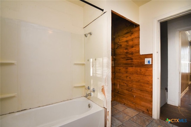 bathroom featuring washtub / shower combination and wooden walls