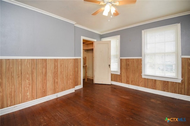 spare room with ornamental molding, dark wood-type flooring, ceiling fan, and wood walls