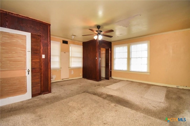 interior space featuring ornamental molding, ceiling fan, and carpet flooring