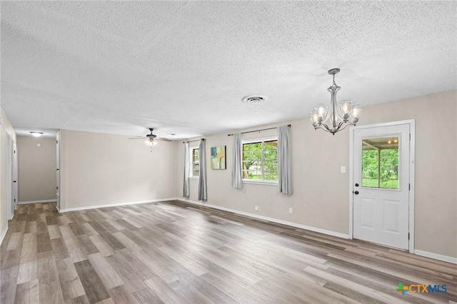 unfurnished living room with a textured ceiling, visible vents, wood finished floors, and ceiling fan with notable chandelier