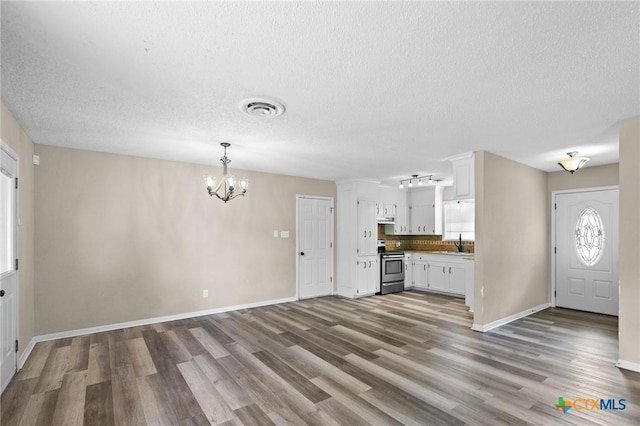 entryway featuring a textured ceiling, a chandelier, wood finished floors, and visible vents