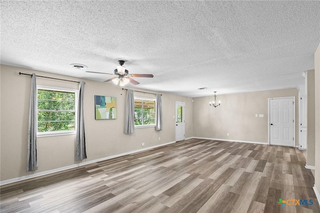 unfurnished room featuring visible vents, plenty of natural light, wood finished floors, and ceiling fan with notable chandelier