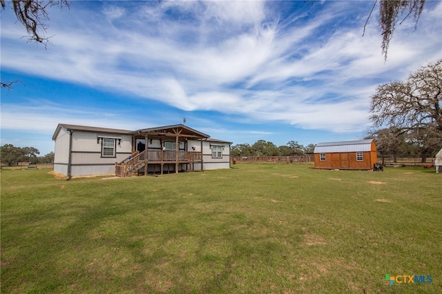 rear view of property featuring an outbuilding, a lawn, and fence