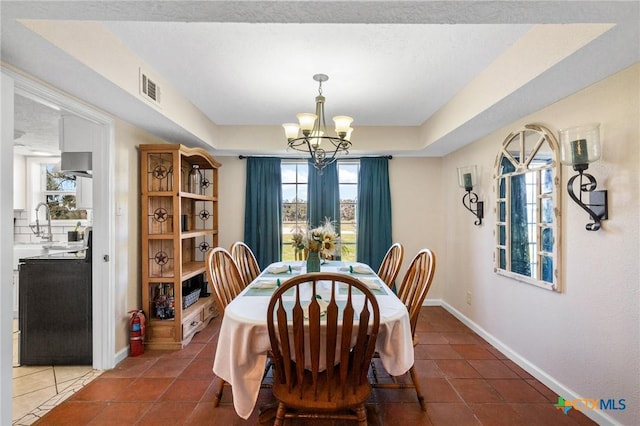 dining space with a chandelier, visible vents, baseboards, tile patterned floors, and a raised ceiling