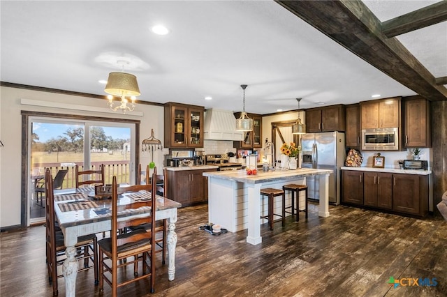 kitchen featuring glass insert cabinets, appliances with stainless steel finishes, light countertops, and dark wood-type flooring