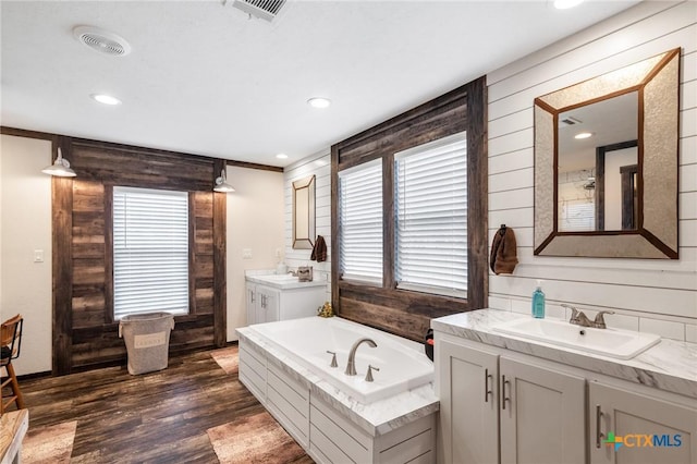 full bath featuring wood walls, a sink, and visible vents