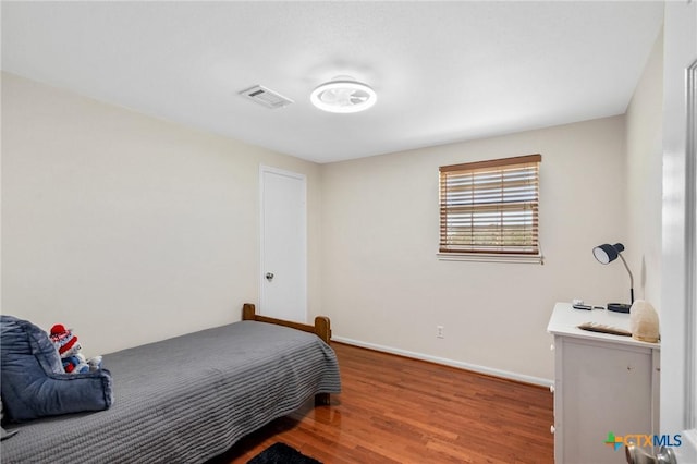 bedroom featuring visible vents, baseboards, and wood finished floors