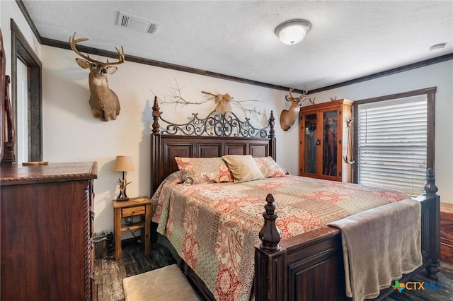bedroom with visible vents, dark wood finished floors, a textured ceiling, and ornamental molding