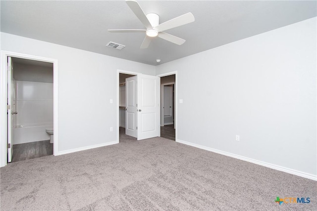 unfurnished bedroom featuring baseboards, carpet flooring, visible vents, and a walk in closet