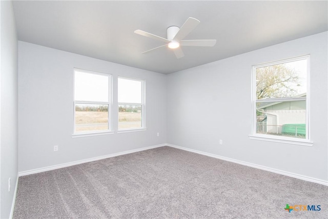 carpeted empty room with ceiling fan and baseboards