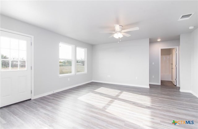 empty room featuring ceiling fan, light wood-type flooring, visible vents, and baseboards