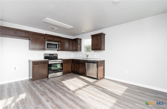 kitchen featuring stainless steel appliances, light countertops, visible vents, a sink, and dark brown cabinets