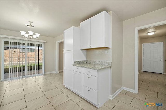 kitchen featuring hanging light fixtures, light stone counters, an inviting chandelier, and white cabinets