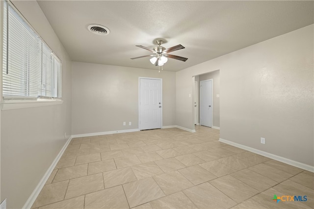 spare room featuring visible vents, ceiling fan, a textured ceiling, and baseboards