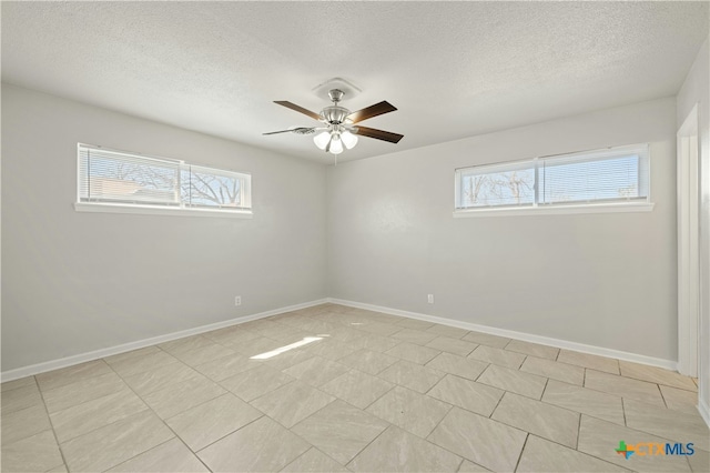 spare room with ceiling fan, a textured ceiling, and baseboards