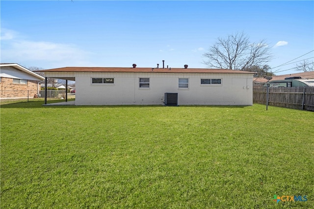 back of house featuring brick siding, a lawn, cooling unit, and fence