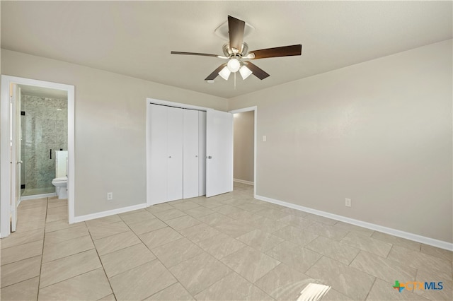 unfurnished bedroom with light tile patterned floors, a closet, connected bathroom, ceiling fan, and baseboards