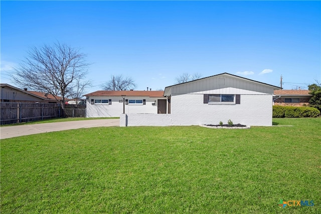 ranch-style home with driveway, brick siding, fence, and a front yard