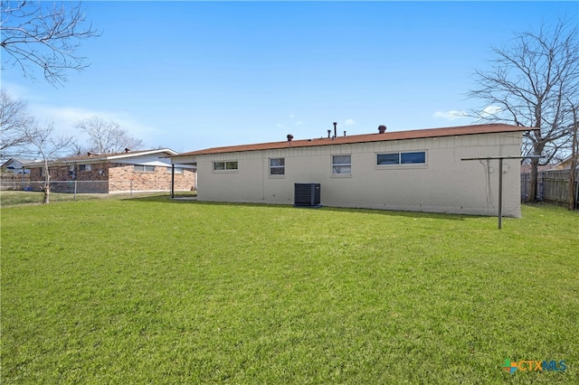 back of property with brick siding, fence, cooling unit, and a yard