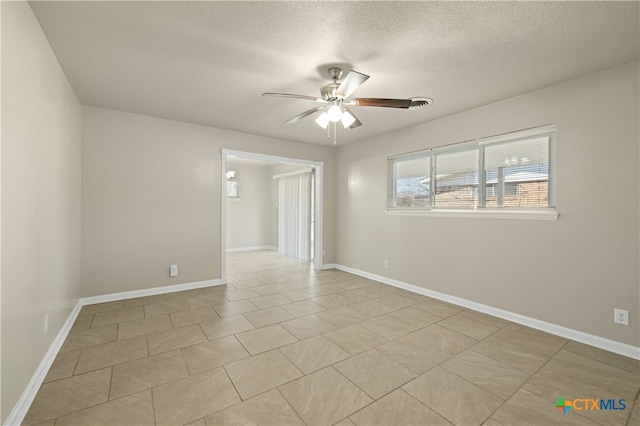 spare room featuring a textured ceiling, a ceiling fan, and baseboards