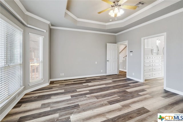 unfurnished bedroom featuring hardwood / wood-style flooring, ceiling fan, crown molding, and a tray ceiling