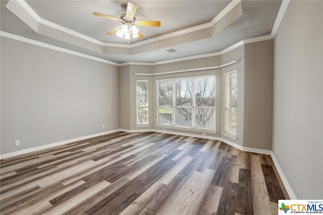 empty room featuring ornamental molding, wood-type flooring, ceiling fan, and a tray ceiling