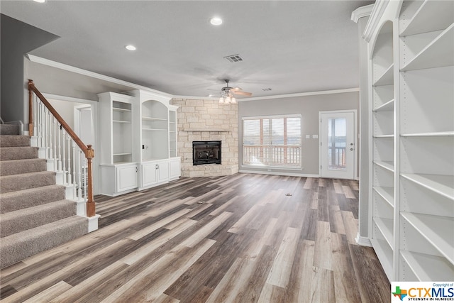 unfurnished living room featuring a fireplace, hardwood / wood-style floors, ceiling fan, and crown molding