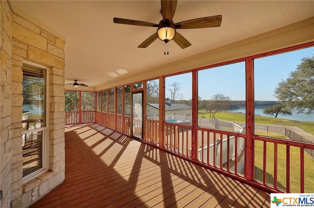 unfurnished sunroom with a water view and ceiling fan