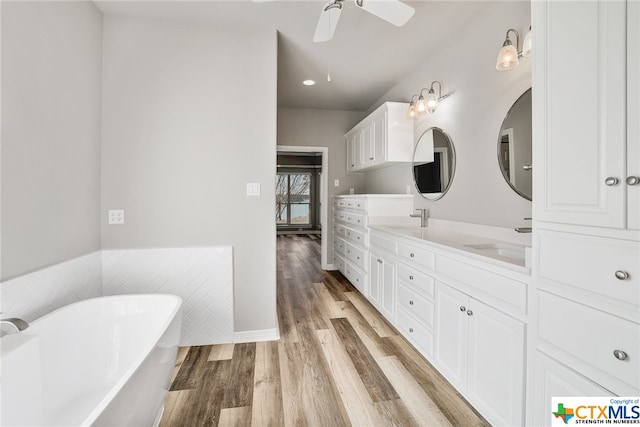 bathroom featuring a bathing tub, vanity, hardwood / wood-style flooring, and ceiling fan