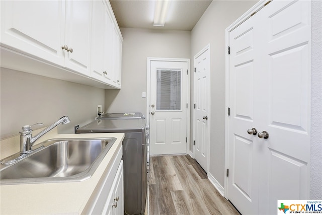 laundry room with cabinets, separate washer and dryer, sink, and light hardwood / wood-style flooring