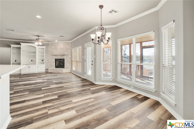 unfurnished living room featuring a fireplace, wood-type flooring, crown molding, and ceiling fan with notable chandelier