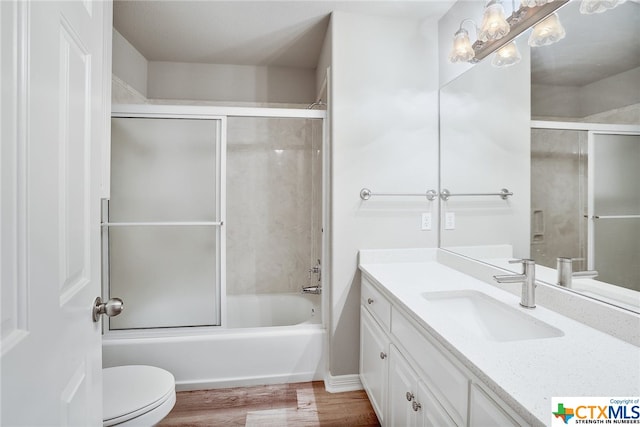 full bathroom featuring shower / bath combination with glass door, wood-type flooring, toilet, and vanity